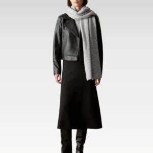 Model wearing black leather biker jacket styled over black skirt and grey turtleneck, showcasing full front outfit view.