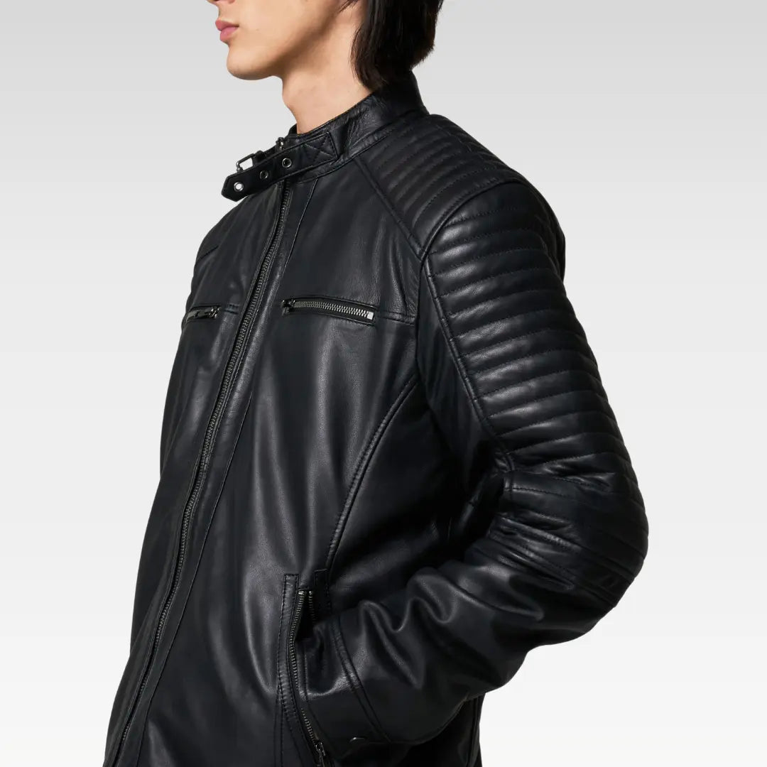 Close-up of black leather racer jacket showing quilted shoulder pattern and aged metal zipper details.