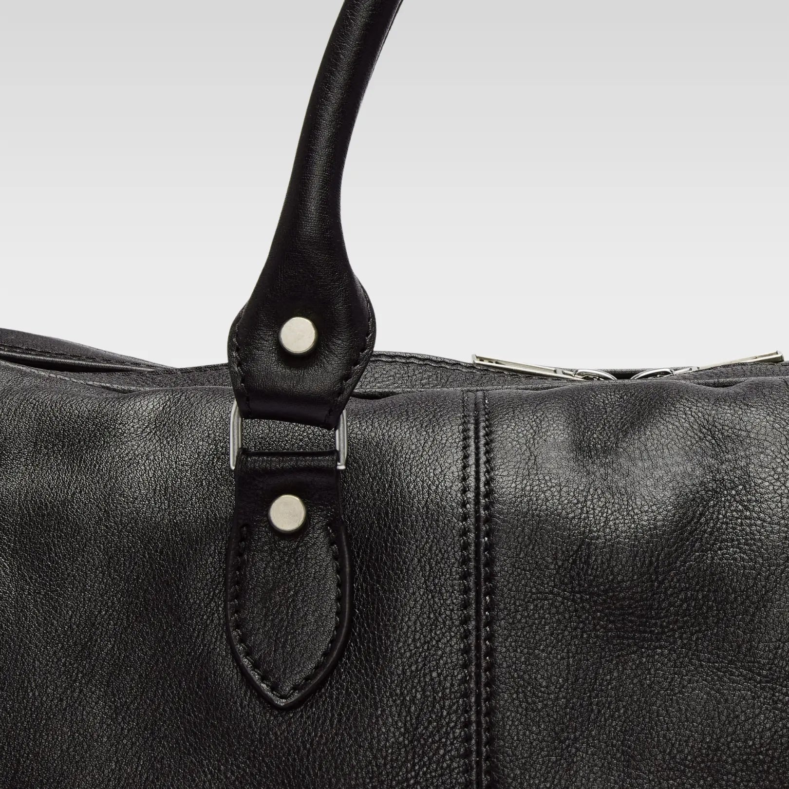 Close-up of the Saddler Black duffle bag’s double-stitched leather strap and hardware, showing durable craftsmanship and premium material.