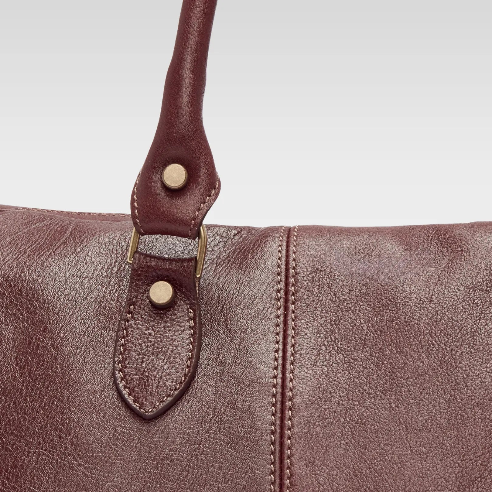 Close-up of the Saddler duffle bag’s double-stitched leather strap and hardware, showing durable craftsmanship and premium material.