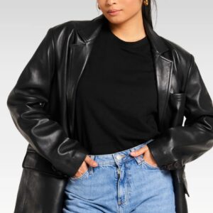 Front view of woman styling oversized sheep leather blazer over black top and blue jeans, combining modern versatility with retro 80s aesthetics.