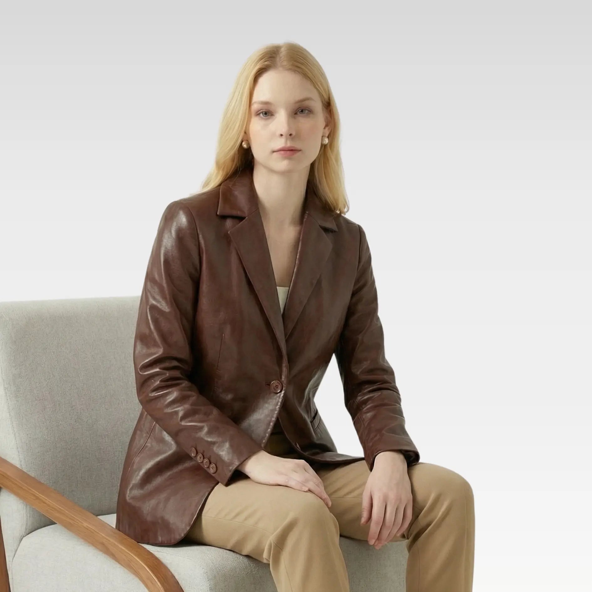 Model sitting wearing a women’s brown leather blazer outfit